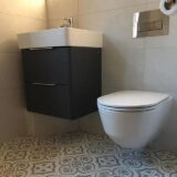 Black floating vanity unit with wall hung toilet. Patterned bathroom floor tile