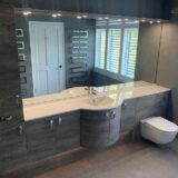 oak effect fitted vanity unit with wall length mirror above. Wall hung toilet