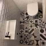 Patterned black and white floor with metro cloakroom tiles. Cloakroom basin with black tap and wall hung toilet