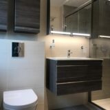 oak effect floating vanity unit above LED mirrored cabinet. Walk in shower and toilet.