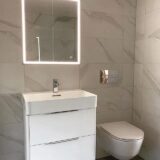 white floating bathroom vanity furniture with recessed LED mirrored cabinet and wall hung toilet next to it