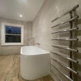 Steel bath, industrial taps and radiator on wall