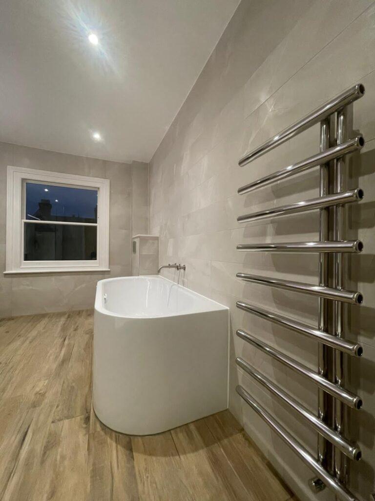 Steel bath, industrial taps and radiator on wall