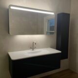 Black wall hung furniture with LED mirrored cabinet and tall boy next to it
