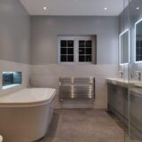 Grey effect fitted furniture with LED mirror above and floating toilet within unit