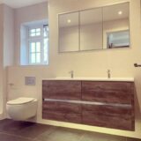 oak effect floating vanity unit with a recessed LED mirror above.