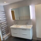 Floating white vanity unit with mirrored vanity cabinet above and tall boy next to it.